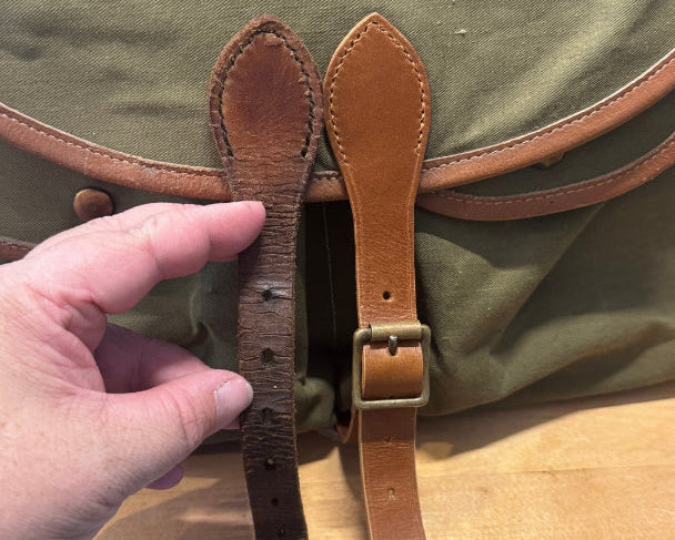 Green canvas bag with brown leather straps on a wooden surface